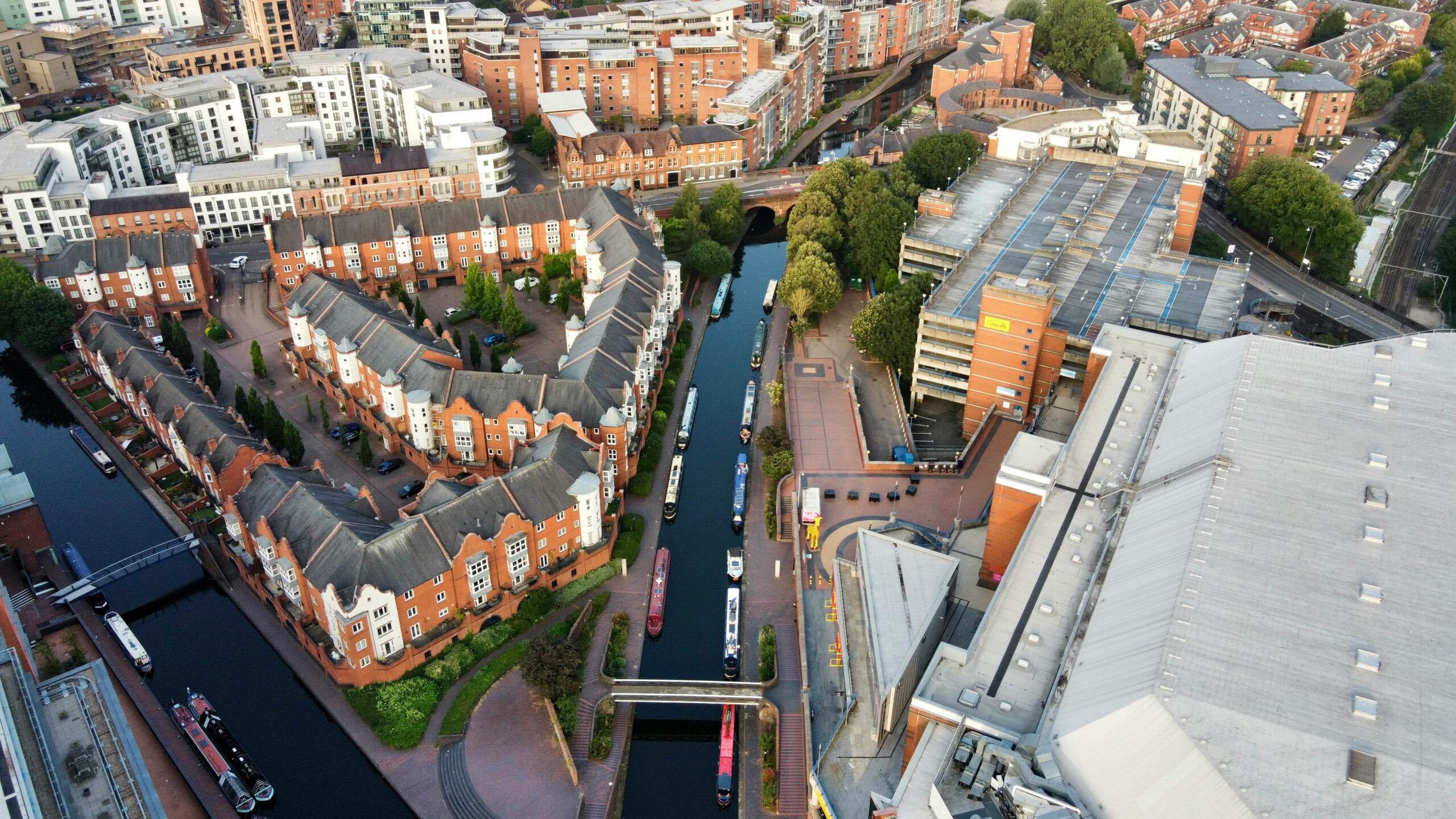 Aerial shot of Birmingham, UK showcasing canals, red-brick houses, and modern buildings.